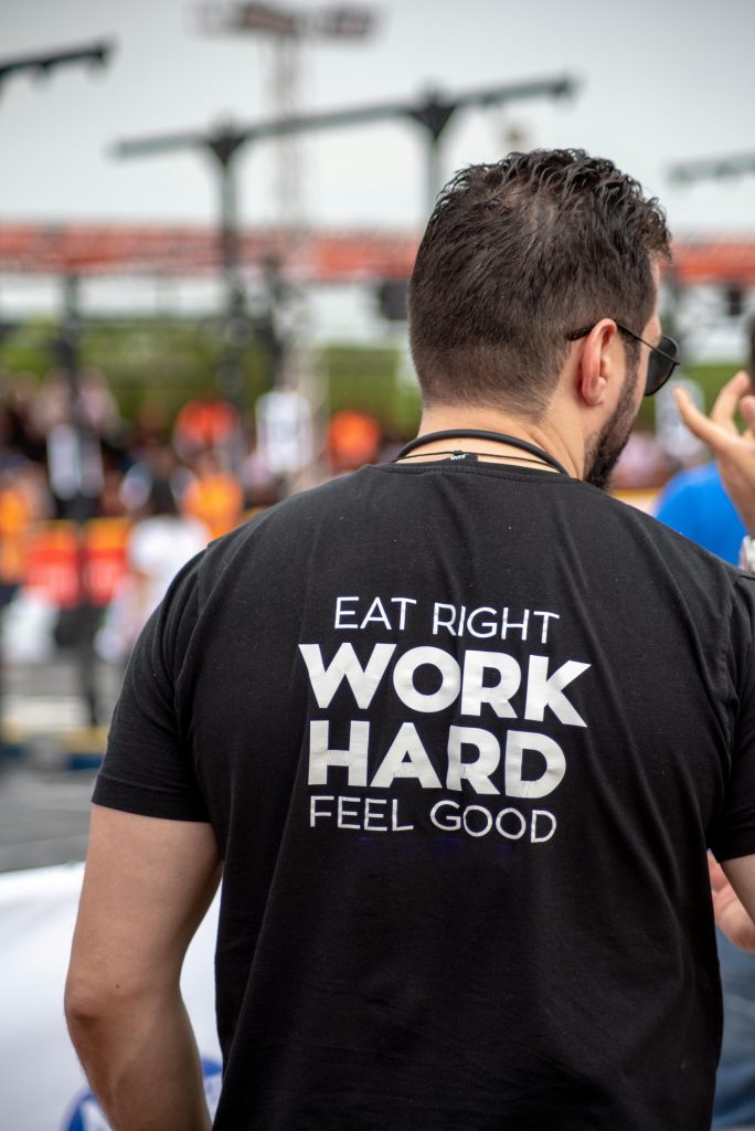 Workers Back view of a man wearing a motivational t-shirt at an outdoor gathering.
